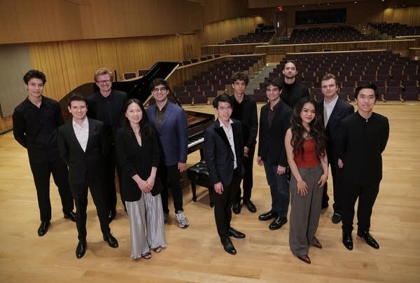 Twelve musicians stand together onstage for a group photo