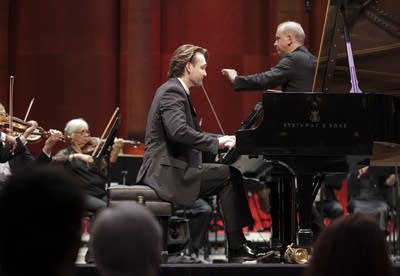 A pianist and an orchestra perform together onstage