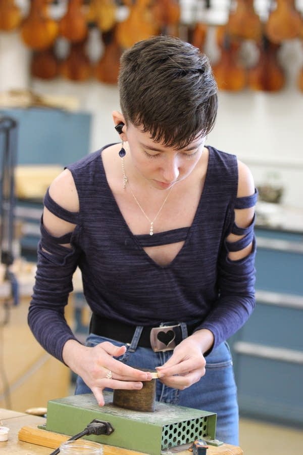 A student works on a component of a violin she is building