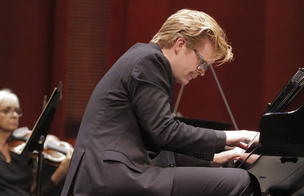 A pianist and an orchestra perform together onstage