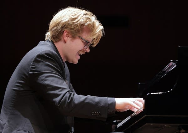 A pianist smiles while performing onstage