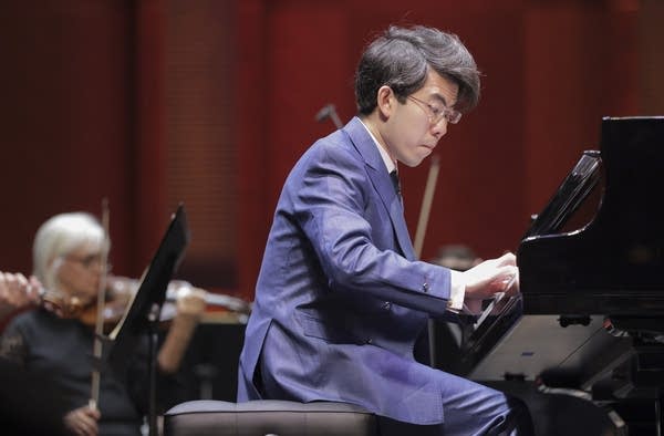 A pianist and an orchestra perform together onstage