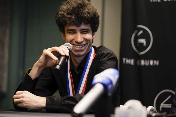 A pianist smiles while answering a question at a press conference